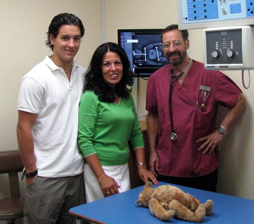 (Left to right) Michael Bertoia, Jeanne Bertoia, and Dr. Hal Blumenthal with the patient, a 1903 Steiff rod bear, whose X-ray is displayed to the rear.