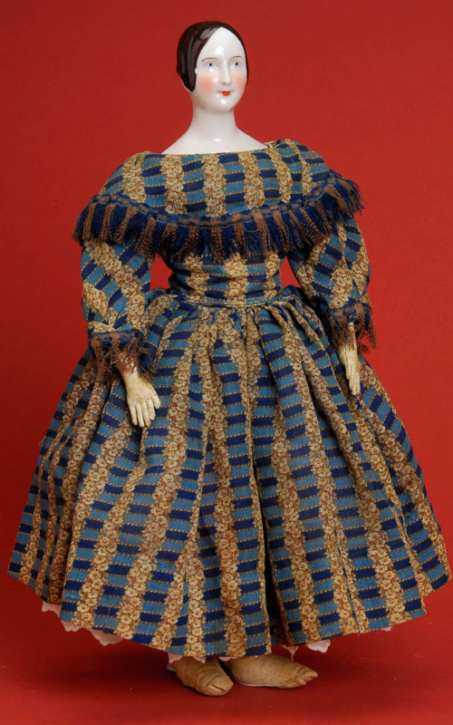 Circa-1840 Rorstrand-style German china doll, 17 inches with very unusual flesh-tone glazed porcelain, possibly KPM, incised 6 on back shoulder, cloth body with kid arms. Wears original floral-printed wool dress with fringe trim. Provenance: Gladys Hilsdorf Collection. Estimate: $5,000-$6,000. 