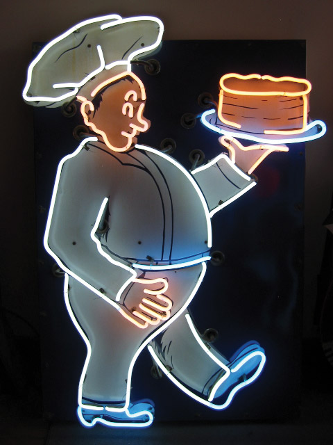 A restored bakery sign, circa 1947, features a glowing baker proudly showing off a cake. Image courtesy David Hutson/Neon Time.