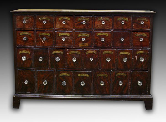 This exceptional 19th-century American apothecary cabinet contains 29 drawers, many with original labels. Grain painted, it is in excellent condition and has a $3,000-$4,000 estimate. It measures 51 inches wide, 36 inches high and 12 inches deep. The grain painted surface covering this apothecary cabinet simulates flamed mahogany. Image courtesy of Midwest Auction Galleries Inc.