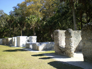 Row of slave quarters adjacent to the crop fields at Kingsley Plantation in Jacksonville, Florida. Structures show effects of erosion, vandalism and subsequent restoration. Public domain image.
