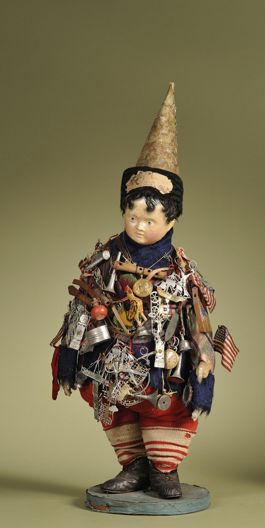 Circa-1852 Kris Kringle doll, Germany, papier-mache shoulder head with molded and painted features, wears wool plaid costume with blue fur trim, paper-covered muslin cone-shaped hat with black fur and paper Christmas die-cut dated 1852, the body covered with approximately 55 period playthings. Height 22 inches. Accompanied by handwritten note reading: “Kris Kringle sends greeting through Cousin Anna to the children, and wishes them a Merry Christmas & Happy New Year - Christmas Eve 1852.” Estimate $6,000-$8,000.