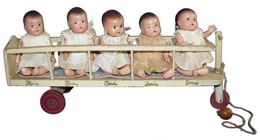 Madame Alexander Dionne Quintuplets dolls in three-wheel painted-wood crib cart with the babies’ names shown on the side. Estimate $450-$650. Image courtesy Mosby & Co. Auctions.