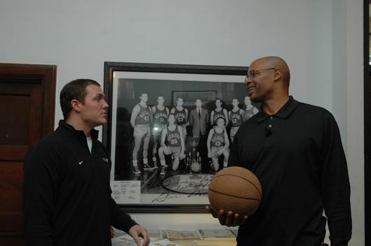Luke Simons of Athletes in Action and Clark Kellogg talk basketball in the lobby of the Hoosier Gym. In the background is a team photo of the Hickory Huskers, including actor Gene Hackman as Coach Norman Dale. Photo by Tom Hoepf.