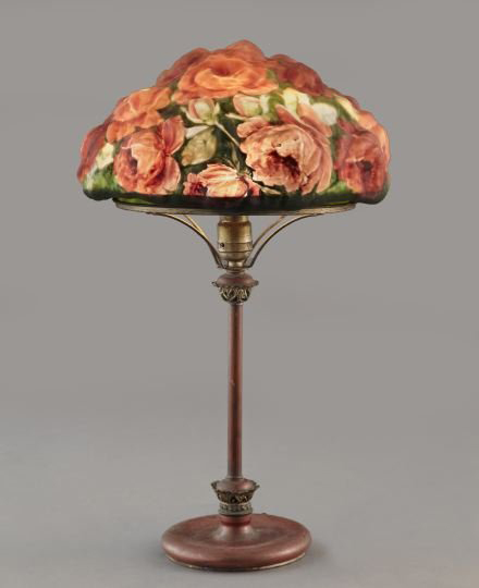 Roses in high relief cover the reverse-painted glass shade of this Pairpoint Puffy table lamp. The 22-inch high base is marked with a cast number only: ‘1116.’ It has a $3,000-$5,000 estimate. Image courtesy New Orleans Auction St. Charles Gallery Inc.