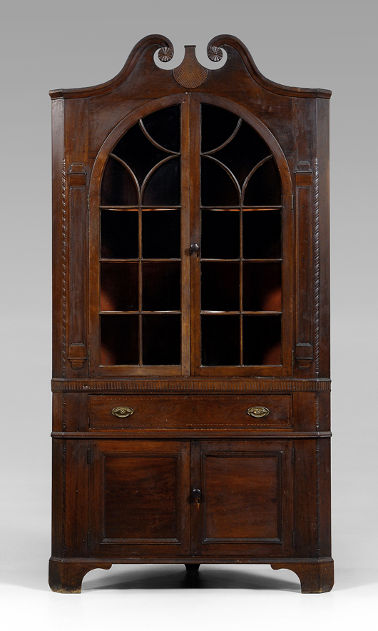 The original blue paint on this Swisegood School corner cupboard can be seen under its orange and red painted surface. The cupboard was made in Davidson County, N.C., circa 1820. Note the rope-carved quarter columns, original brasses and original bracket feet. It has a $40,000-$60,000 estimate.