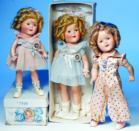 Dressed in a blue pleated ‘Curly Top’ costume, the 16-inch Shirley Temple doll in the middle has the original pin and box. In mint condition, this Shirley has a $700-$1,200 estimate. Image courtesy of Frasher’s Doll Auction.