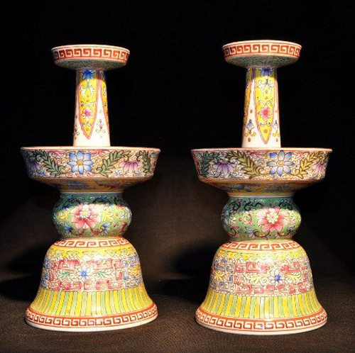 Each of these Famille Rose candlesticks is finely painted with large lotus blooms on dense scrolling leafy stems on a rich lemon-yellow ground. The 9 3/4-inch sticks have a $10,000-$12,000 estimate. Image courtesy Wichita Auction Gallery.