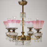 Hanging Four-Arm Chandelier, stamped brass with multi-colored stones in exceptional condition. Fitted with two pair pattern molded fonts and mother-of-pearl with satin finish shades, and with matching chimneys and prisms. 34 1/2