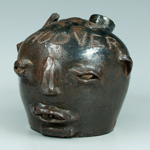 Shown here is an example of an Albany slip stoneware face jug with rock eyes and teeth below incised name "Hoover." Origin: Lincoln County, N.C., circa 1936, 6-1/2 x 6-3/4 inches. Possibly the work of Casey Meaders (1889-1945) who moved from White County, Ga., to Catawba County, N.C., in 1920 and worked as a potter from 1920-1940. "Hoover" probably refers to President Herbert Hoover. This jug sold for $10,200 in Brunk Auctions' March 24, 2007 sale. Image courtesy LiveAuctioneers Archive and Brunk Auctions.