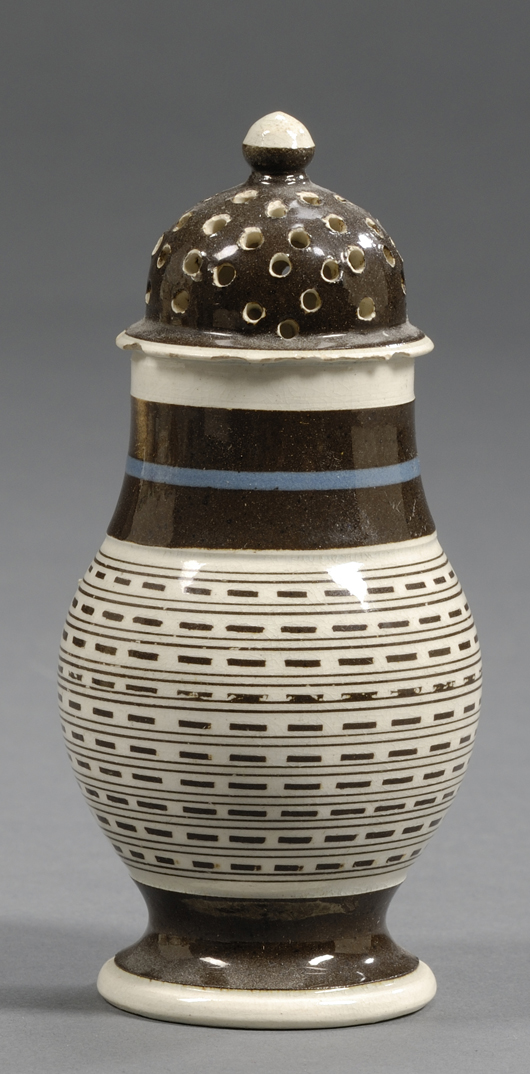 A baluster form pepper pot, made around 1800, has a pearlware body circled by an engine-turned pattern filled with dark slip: $948. Image courtesy Skinner Inc.