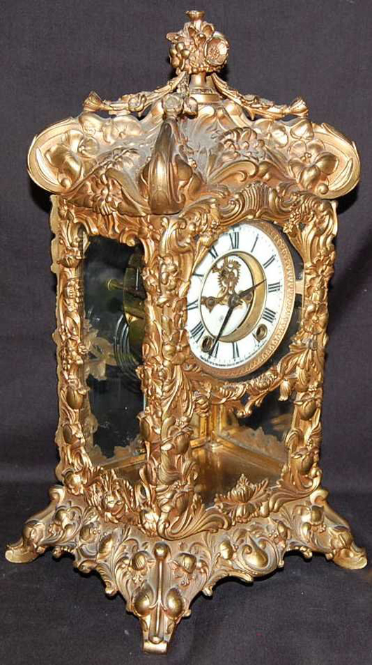 Fabulous relief work is evident in this 16-inch-high gilt clock case by Ansonia. The mantel clock has a mercury pendulum and open escapement. It has a 500-$1,000 estimate. Image courtesy of Four Seasons Auction Gallery.