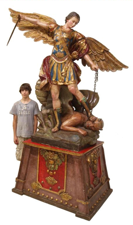 Excellent polychromed-wood religious statue of St. Michael the Archangel standing on Lucifer, carved and signed by Agustín Parra Echaurri, (Mexico, b.1960-) after a painting by Guido Reni (1575-1642), heavily gilded detail throughout, wood sword, standing on gilt-accented base. Stands 9ft. 5 inches tall. Estimate $10,000-$15,000. Note: A companion piece is offered in this sale. Image courtesy of Austin Austin Gallery.