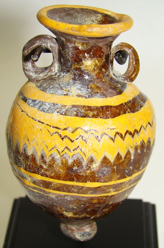 Minor invisible repair has been made to this Eastern Mediterranean core glass Amphoriskos, which dates to circa 600-400 B.C. Having a deep yellow-brown color with golden yellow and white zigzag bands, this ancient jar is only 2 5/8 inches high. It has a $4,000-$5,000 estimate. Image courtesy of Malter Galleries Inc.