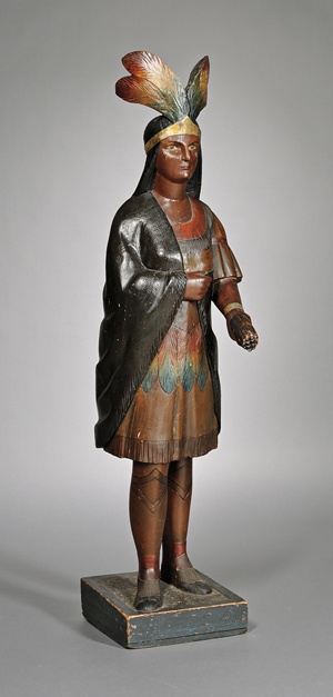 Polychrome-painted carved wooden Indian tobacconist figure, American, late 19th century, carved feather headdress and apron, fringed cape and dress, one hand holds a bundle of cigars, overall height (including plinth) 64¾ inches. Estimate $8,000-12,000. Image courtesy of Skinner Inc.