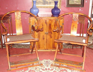 A pair of Huanghuali hunting chairs, which sold for $26,880, flanks a Huanghuali two-door cupboard, which hit $2,800. Image courtesy of Finney’s Auction Service.