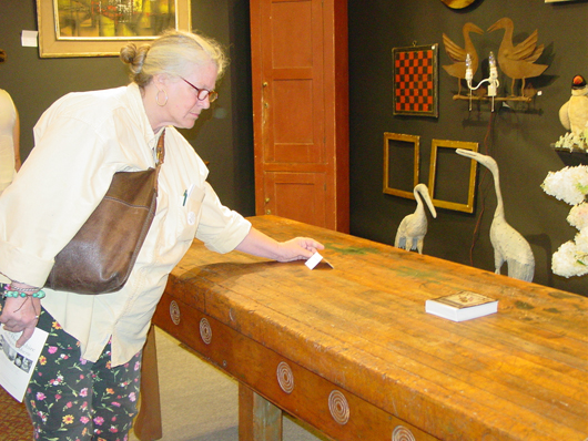 A shopper checks the price ($3,800) of a late-19th-century country store work table, block top on cherry base. From Jef and Terri Steingrebe, Springfield, N.H. Photo copyright Catherine Saunders-Watson.