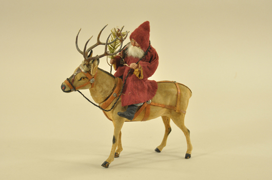 Finely crafted, an early 10-inch by 11-inch German Santa riding a reindeer candy container wears a fabric suit, sports a rabbit-fur beard, and separates at the neck for access to candy. Estimate $3,200-$3,500. Bertoia Auctions image.