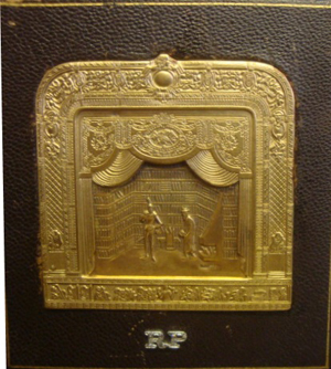 Marked 14K and artist signed by jeweler Henryk Kaston in gold, this bas relief from the Old Metropolitan Opera, is initialed ‘R.P.’ for Roberta Peters in diamond chips below. The piece is mounted in leatherette base as a paperweight and has a $600-$900 estimate. Image courtesy of Clarke Auctions.