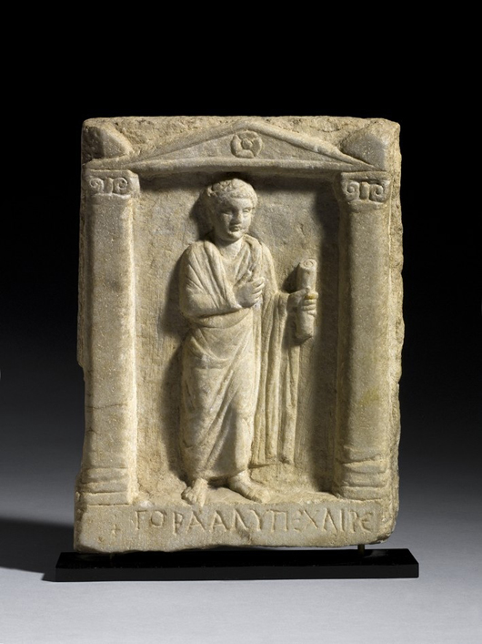 This Roman carved marble stele of a toga-clad figure holding a scroll, second or third century, is included in Charles Ede's Christmas catalog priced at 6,750 pounds ($10,850). Image courtesy Charles Ede Ltd.