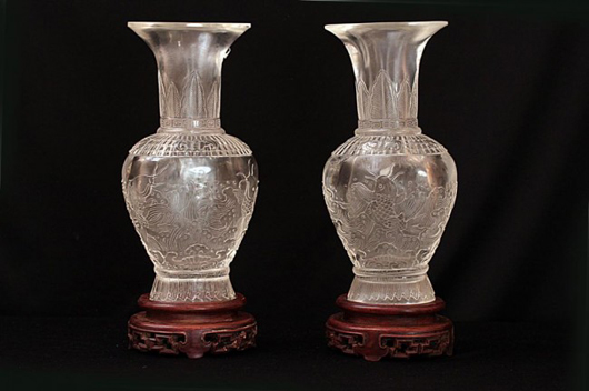Pair of Chinese rock crystal vases, Republic Period, 13 1/2 inches high, decorated with carved fishes against waves, on carved wooden stand. Estimate: $5,000-$7,000. Image courtesy of Artingstall & Hind.