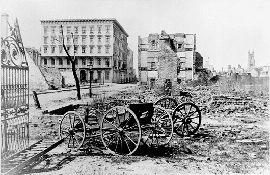 Historic 1865 photo taken by George N. Barnard (1819-1902) showing the ruins of Mills House and nearby buildings in Charleston, S.C., at the end of the Civil War. A shell-damaged carriage and the remains of a brick chimney are in the foreground.