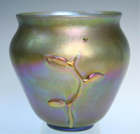 Tiffany Favrile golden iridescent glass vase with foliage applique, 19th century, marked and numbered,  5 1/2 inches high x 5 1/4 inches diameter. Estimate: $2,000-$3,000. Image courtesy of Showplace Antique & Design Center.