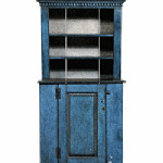 Worn blue paint can be seen on this country cupboard. The top part is shallower than the bottom, giving it the name stepback cupboard. It sold for $1,180 at a Brunk auction in Asheville, N.C.