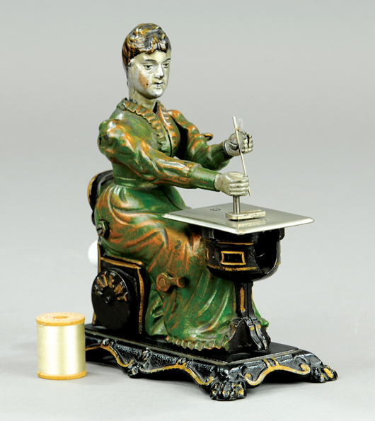Cast-iron woman at sewing machine, attributed to Sandt, rear lever activates head and hand motions when turned; side of chair actually holds spool of string for sewing cloth items. One of very few known examples. 7½ inches high. Estimate $8,000-$10,000. Bertoia Auctions image