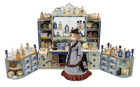 Parisian perfumery room box stocked with various fragrances, powders, soaps and pomades; tended by a well-dressed bisque-head doll, est. $2,000-$3,000. Noel Barrett Auctions image.