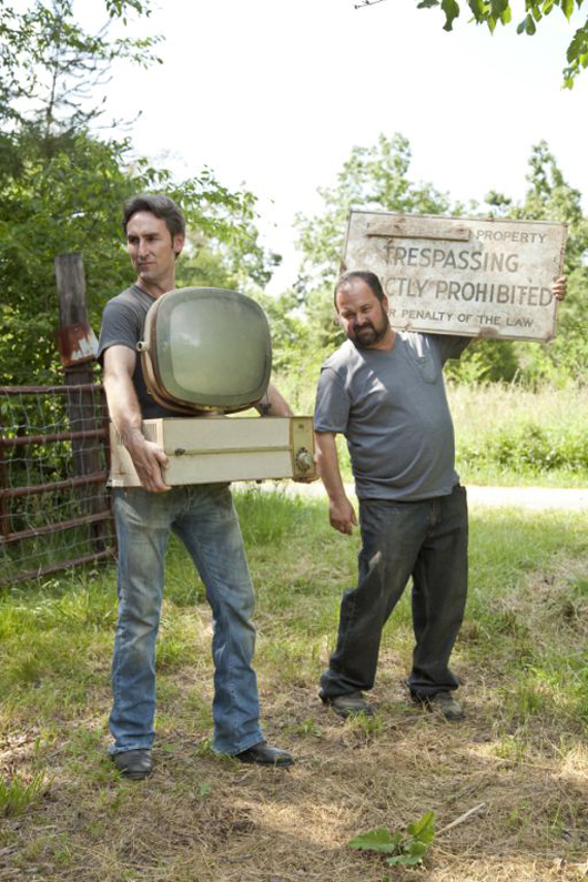 Mike Wolfe and Frank Fritz haul away their fresh pickings, a vintage TV and an old sign. Image courtesy of HISTORY.