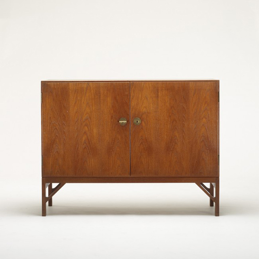 Børge Mogensen cabinet for Fredericia Stolefabrik, Denmark, circa 1940, teak, brass, 48 inches wide x 18 inches deep x 37 inches high. Cabinet features two doors concealing two shelves and three drawers. Estimate: $5,000-$7,000. Image courtesy of Wright.
