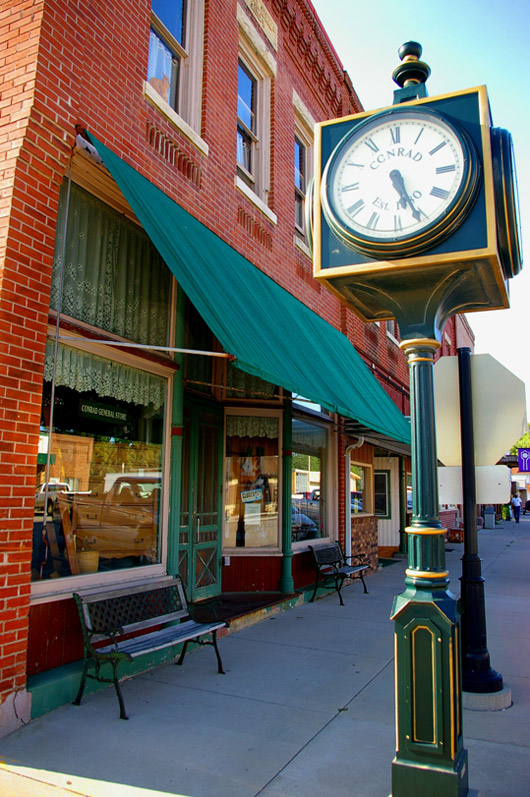 A quaint and locally revered stretch of downtown Conrad, Iowa that includes the Conrad General store, with white lace curtains green awning. Image courtesy of City of Conrad, Iowa.