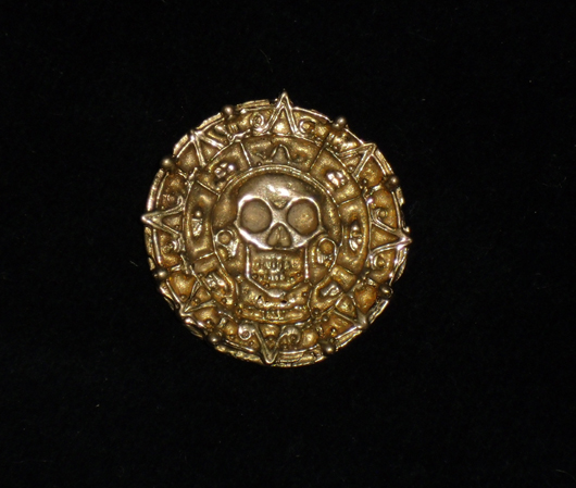‘Pirates of the Caribbean: The Curse of the Black Pearl’ (2003), screen-used cursed Aztec gold coin, 1 1/2 inches diameter, metal painted gold, includes documentation. Image courtesy of Premiere Props.