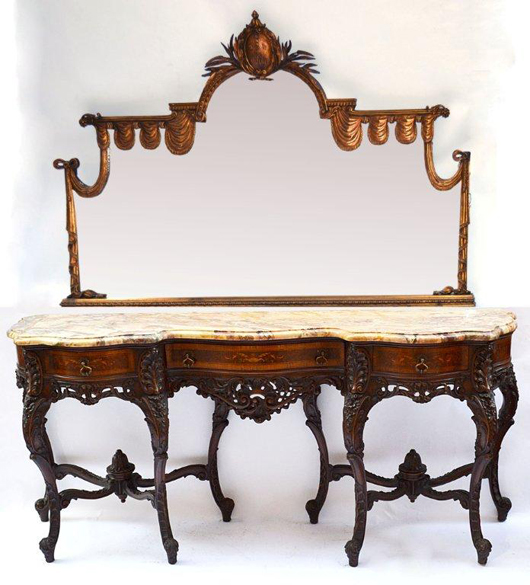 Elaborate Italian inlaid console sideboard with marble top, on two pedestals of cabriolet legs joined by bowed stretchers surmounted with finials. The massive gilt mirror is decorated with repeating swags, jabot and topped with an elaborate cartouche. Its catalog estimate tops out at $5,000.