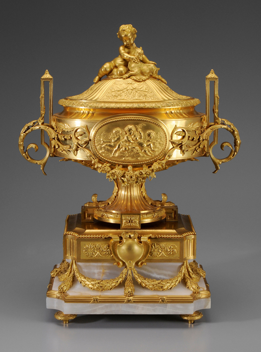 Trophies of music and cupids frolicking in waves decorate the sides of this French gilt bronze urn in the style of Louis XVI. The 29 1/2-inch-tall urn opened at $20,000 and sold for $30,000. Image courtesy of Brunk Auctions.