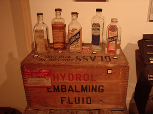 An assortment of early 20th-century embalming fluid bottles. Image courtesy of Wikimedia Commons.
