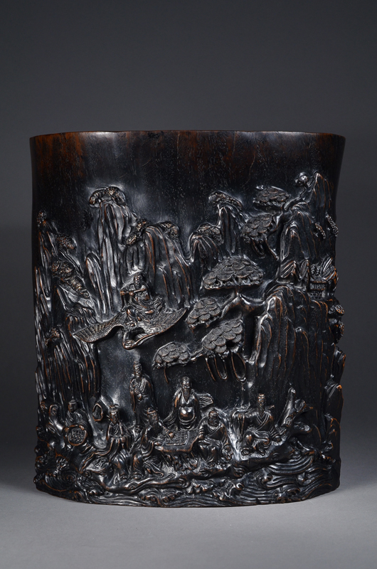 Massive Chinese zitan brush pot, front carved with large scene of eight Daoist Immortals at leisure in mountain grotto, dated 1896, 29 cm (11 1/2 inches) high. Image courtesy of 888 Auctions.