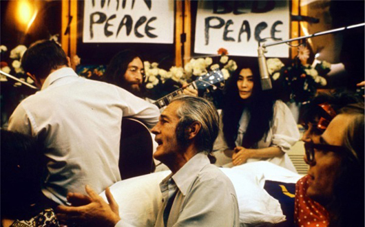 John Lennon and Yoko Ono record 'Give Peace a Chance' in a Montreal hotel in 1969. In the background is a 'Bed Peace' sign that Lennon made. Pictured in the foreground are Timothy Leary (center) and Paul Williams. Photo by Roy Kerwood. This file is licensed under the Creative Commons Attribution 2.5 Generic license.   
