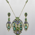 Frank Gardner Hale jeweled and enameled bold Arts and Crafts suite, circa 1920. A pendant necklace and earrings composed of a principal demantoid garnet, blue-green tourmalines and sapphires arranged among 18K gold fronds in shades of blue and green guilloche enamel. Estimate: $30,000-$40,000. Rago Arts and Auction Center.