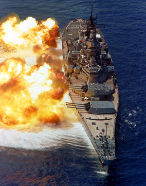 The battleship USS IOWA firing its 16-inch guns during a firepower demonstration in August 1984. Image courtesy of Wikimedia Commons.