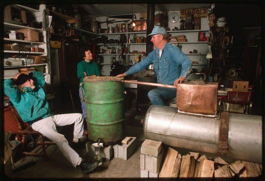 John Bowman (right), in his garage, explaining how a moonshine still works to Mary Hufford and John Flynn. Courtesy of the American Folklife Center, Prints and Photographs Division, Library of Congress, Washington, D. C. 