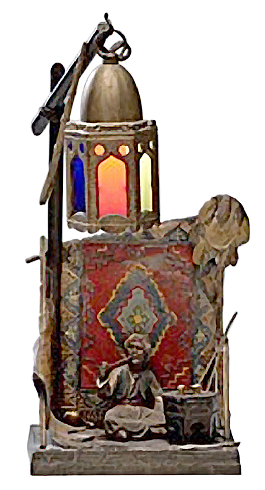 This cold-painted figure depicts an Arab man with a pipe seated in front of a rug and a lit tower. The lamp is 13 inches high and 6 inches wide. It's unmarked but still sold in October 2011 for $763 at Cowan's Auctions in Cincinnati.