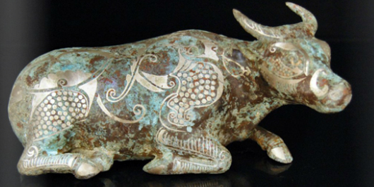 Bronze recumbent buffalo stoutly cast with legs and tail tucked, is accented with silver inlay of phoenix motifs. Image courtesy Gianguan Auctions.