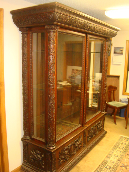 Monumental R.J. Horner carved oak two-door glass collector's cabinet on a two-drawer base. Image courtesy of Tim's, Inc.