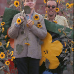 Andy Warhol in a field of black-eyed Susans with Taylor Mead holding an early “Flowers” canvas as a backdrop in Queens, New York. Title: Warhol Flowers VII Location: Flushing, Queens Medium: Chromogenic Print Edition: 60 with 7 Artist Proofs Size: 24 x 16 inches Executed: 1964 Printed: 2012 Copyright 2010 William John Kennedy / Courtesy of Kiwi Arts Group