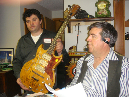 Auctioneer Tim Chapulis (right) fields bids for a vintage guitar signed by members of '60s rock band Iron Butterfly, $604. Image courtesy Tim's, Inc.