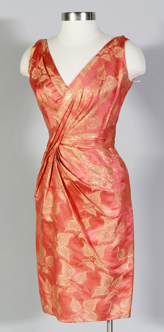 Ceil Chapman cocktail dress, coral color silk with gold metallic stitching in leaf design, coral colored silk lining, double v-neck front and back, rushing on bodice, 15-inch bust x 12-inch waist x 38 inches long. Chapman started her own business in 1940, costumed the musical ‘South Pacific’ and specialized in cocktail dresses. Estimate: $200-$300. Image courtesy Kaminski Auctions.   