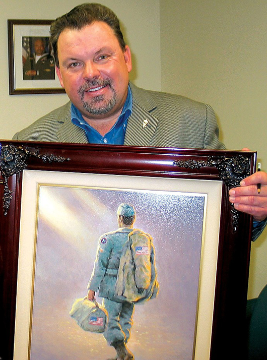 October 2005 USO photo of Thomas Kinkade with an artwork that he described as depicting an American armed forces member returning home for Christmas.