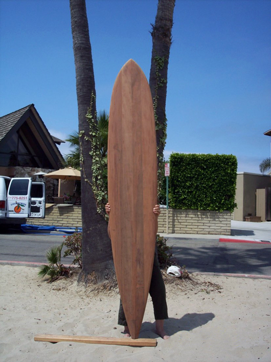 1980 replica redwood Hot Curl surfboard. There is a dolphin and extended inlays in the deck. Estimate: $8,000-$10,000. Waverider Auctions image.